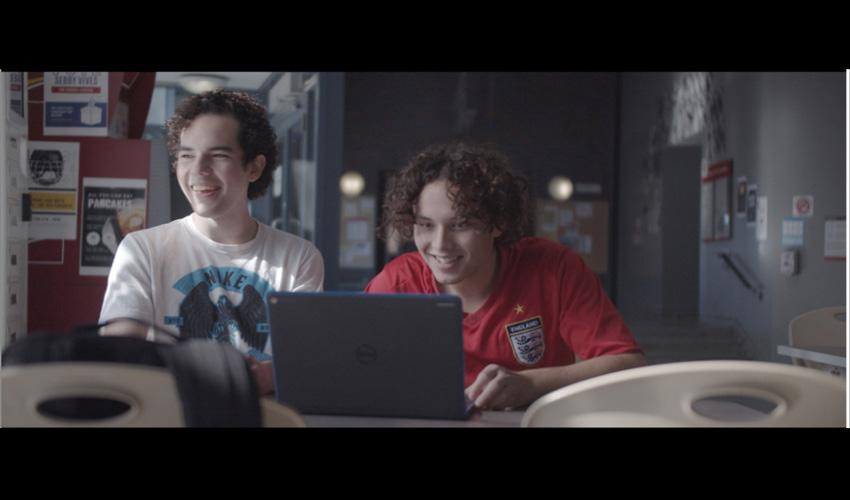 Two teens stare at a laptop